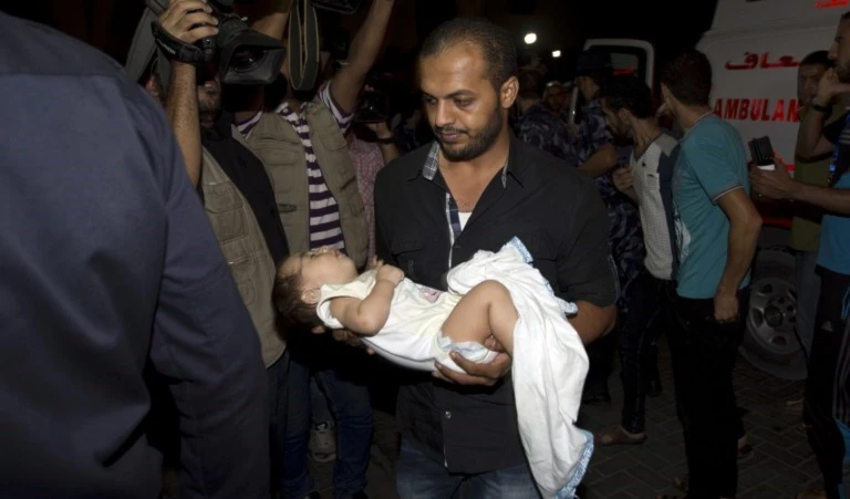 فلسطيني يحمل طفلاً جريحاً في غارة إسرائيلية أمس (أ ف ب) فلسطيني يحمل طفلاً جريحاً في غارة إسرائيلية أمس (أ ف ب)