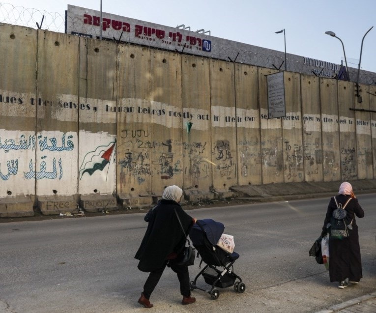 إمرأة فلسطينية تسير على جانب الجدار الإسرائيلي الفاصل في قرية الرام الفلسطينية في (أ ف ب). إمرأة فلسطينية تسير على جانب الجدار الإسرائيلي الفاصل في قرية الرام الفلسطينية في (أ ف ب).